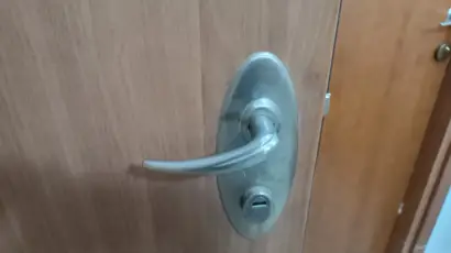 ידית דלת ממד ממתכת עם מפתח, על רקע דלת עץ. מתאים לתיקון דלת ממד בבאר שבע.